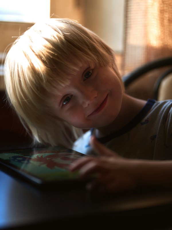 Young boy confidently using tablet for sensory-calibrated AAC communication
